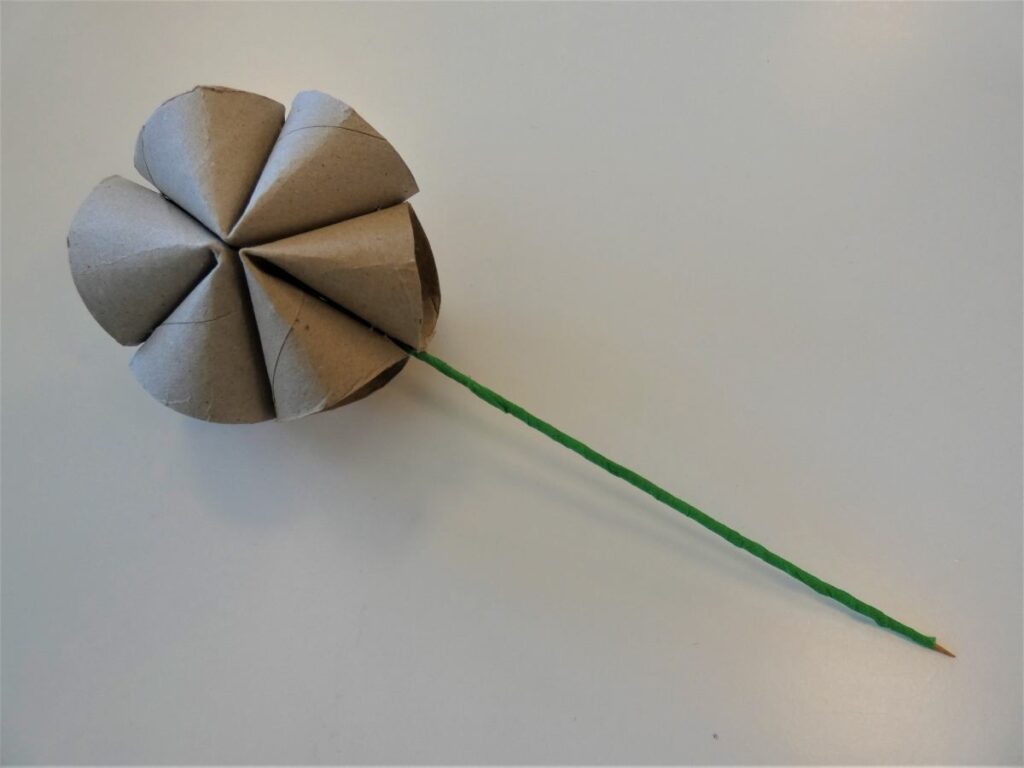 Rolki z papieru połączone w kształt kwiatu z wbitym zielonym patyczkiem