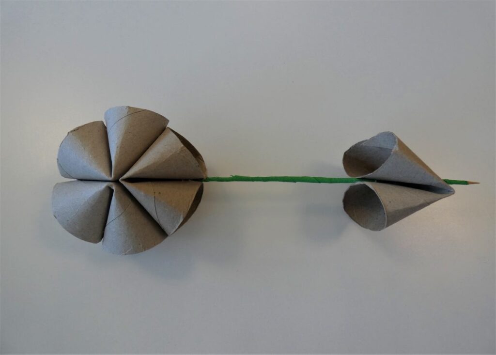 Rolki z papieru połączone w kształt kwiatu z wbitym zielonym patyczkiem