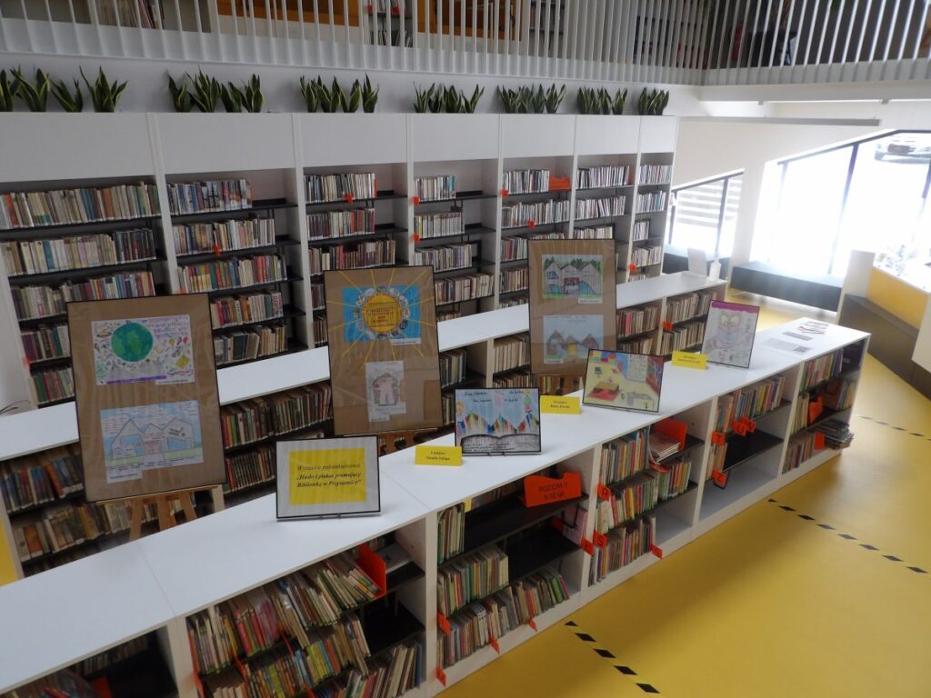 Widok wnętrza biblioteki, regały z książkami, na regałach fotoramy z plakatami